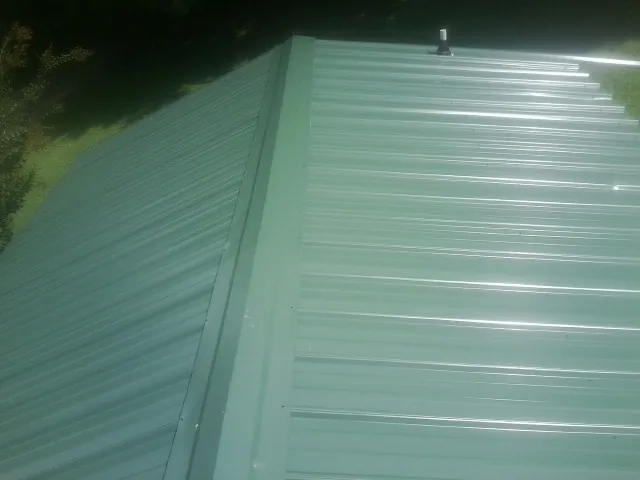 New green metal panels meeting at the ridge of a roof — Flat Roof Repair work by our crew in Seabrook