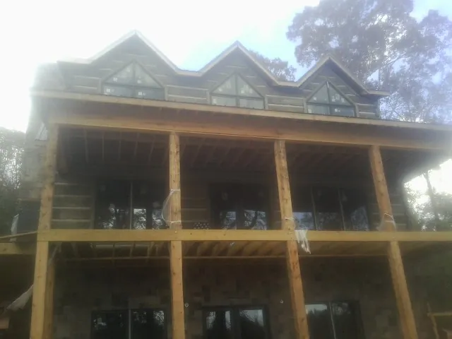 Dormers and porch framing on a large log home under construction — Roof Coating work by our crew in Seabrook